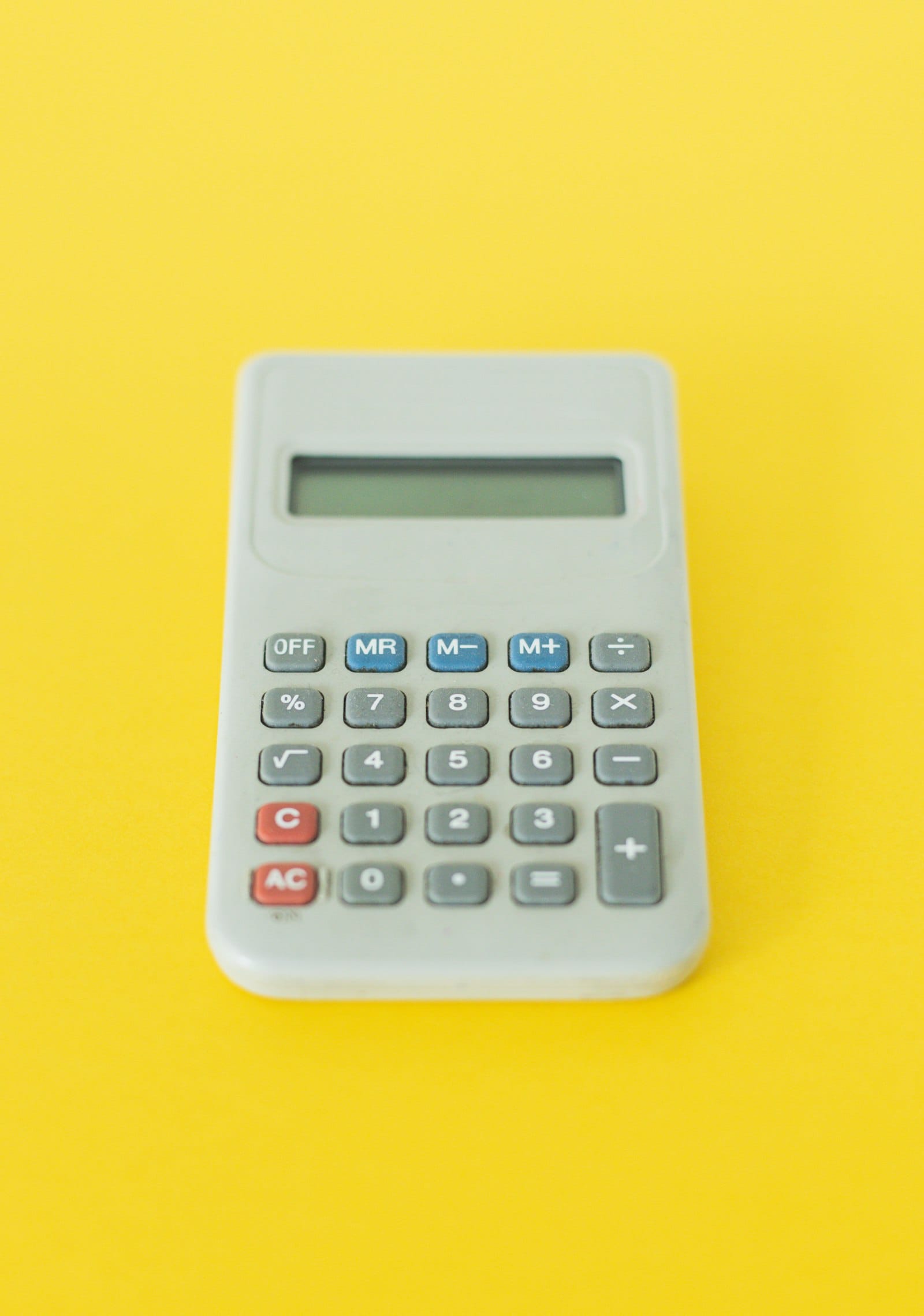 A gray handheld calculator on a yellow background