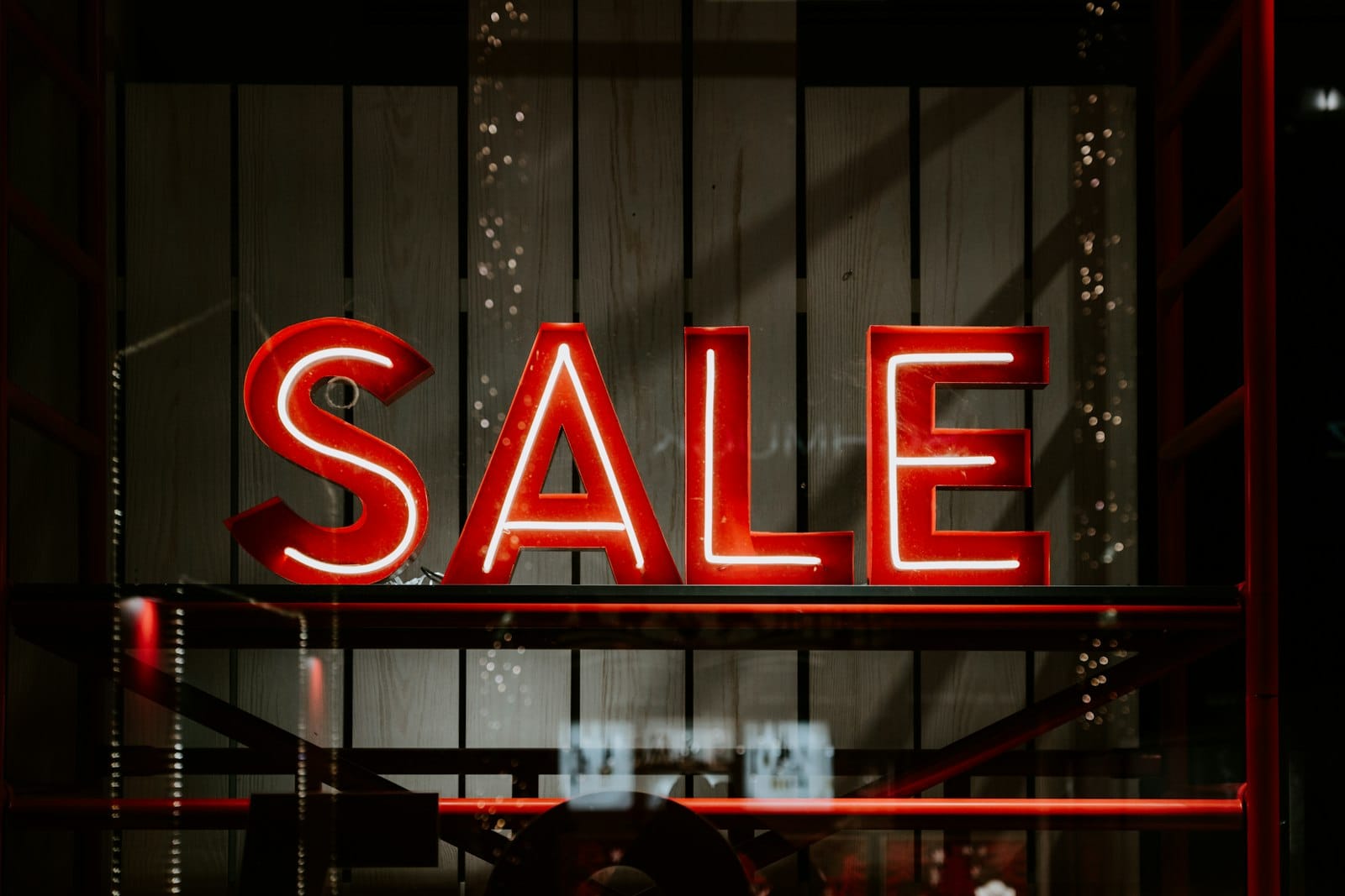 A red-and-white neon SALE sign in a shop window