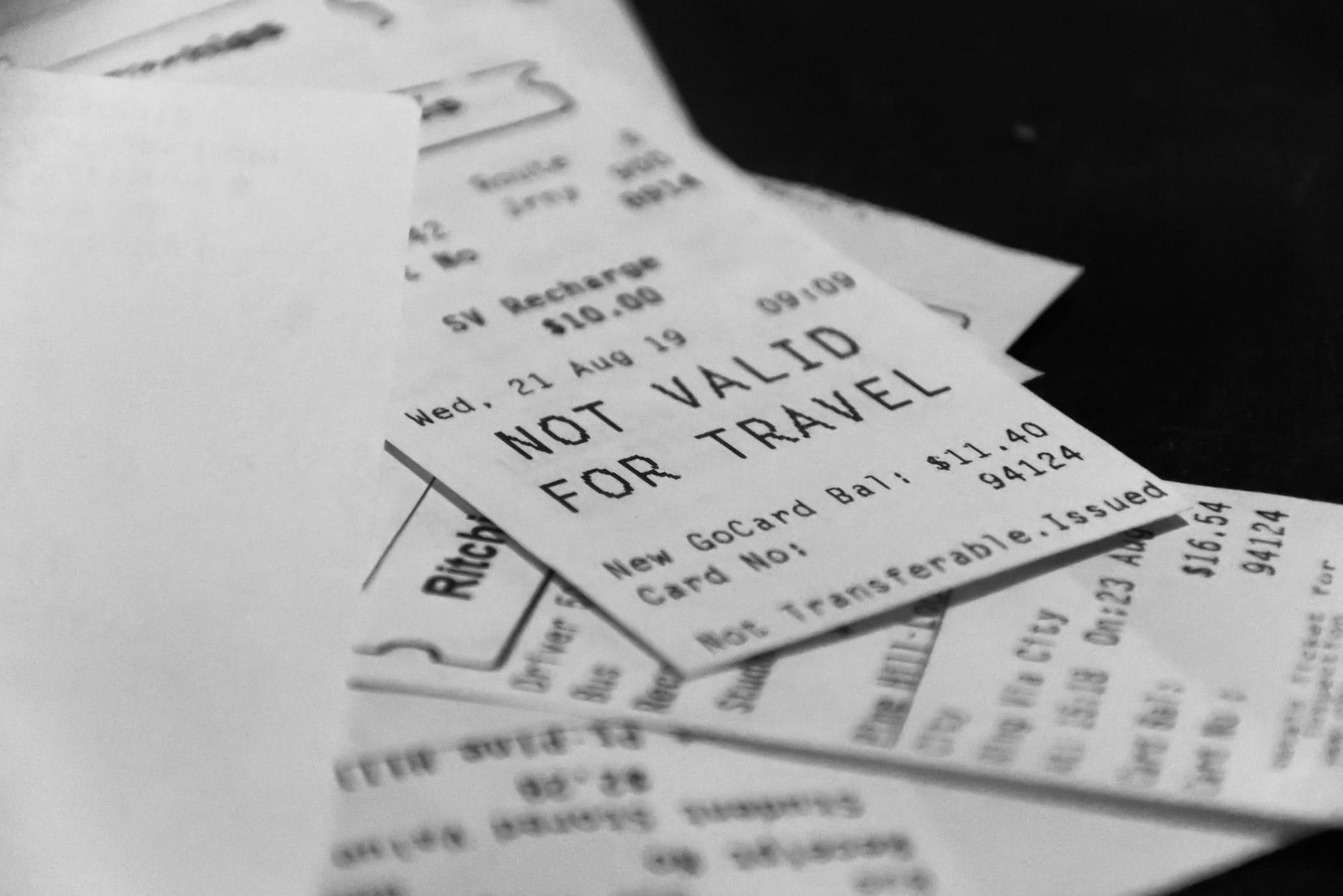 A close-up stack of printed receipts and transit tickets. The top slip shows SV Recharge $10.00, a GoCard balance of $11.40, and NOT VALID FOR TRAVEL. Another slip shows $16.54.