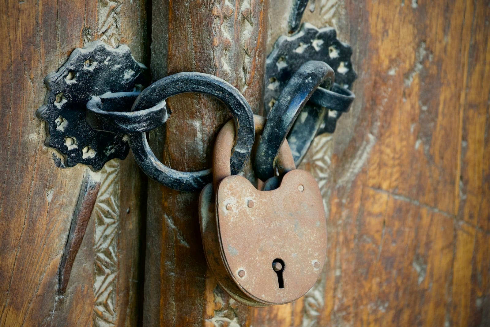 A rusted padlock securing a wooden door