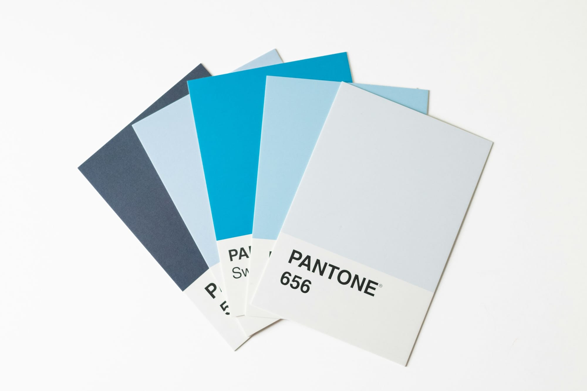Five fanned Pantone color swatches in stacked shades of blue on a white background