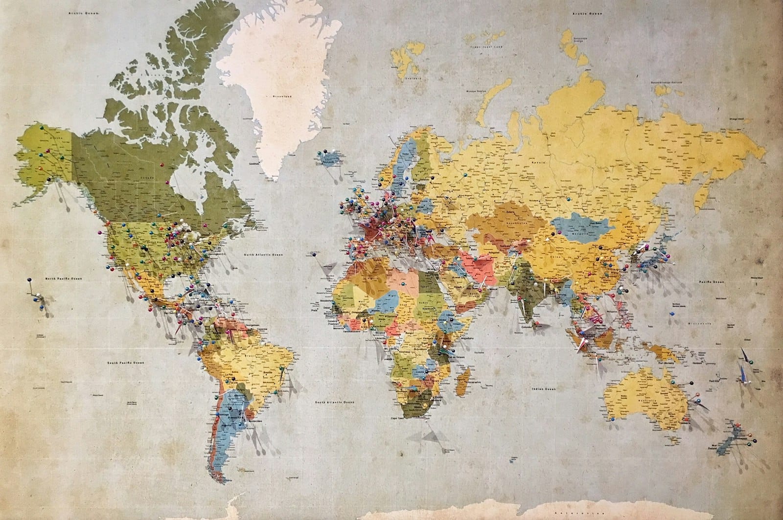 A vintage world map covered in colorful location pins