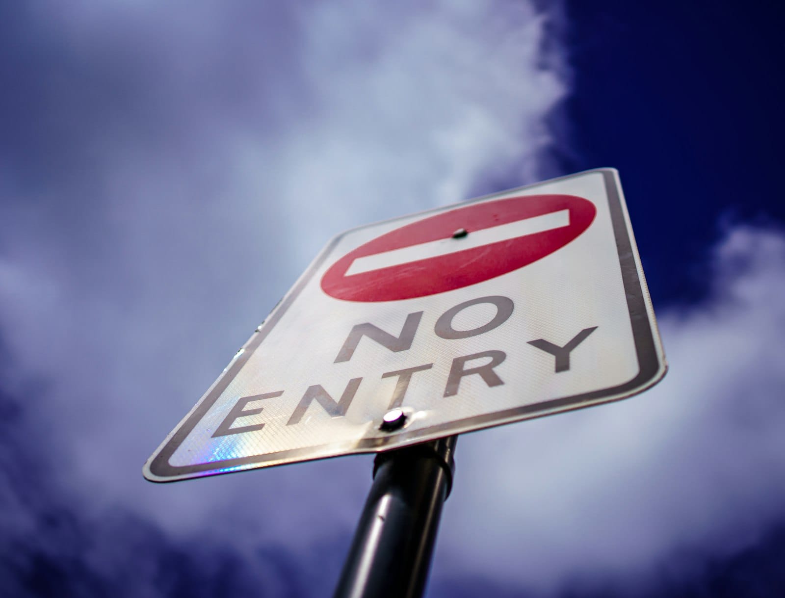 A white NO ENTRY sign with a red circle, photographed against a dark sky