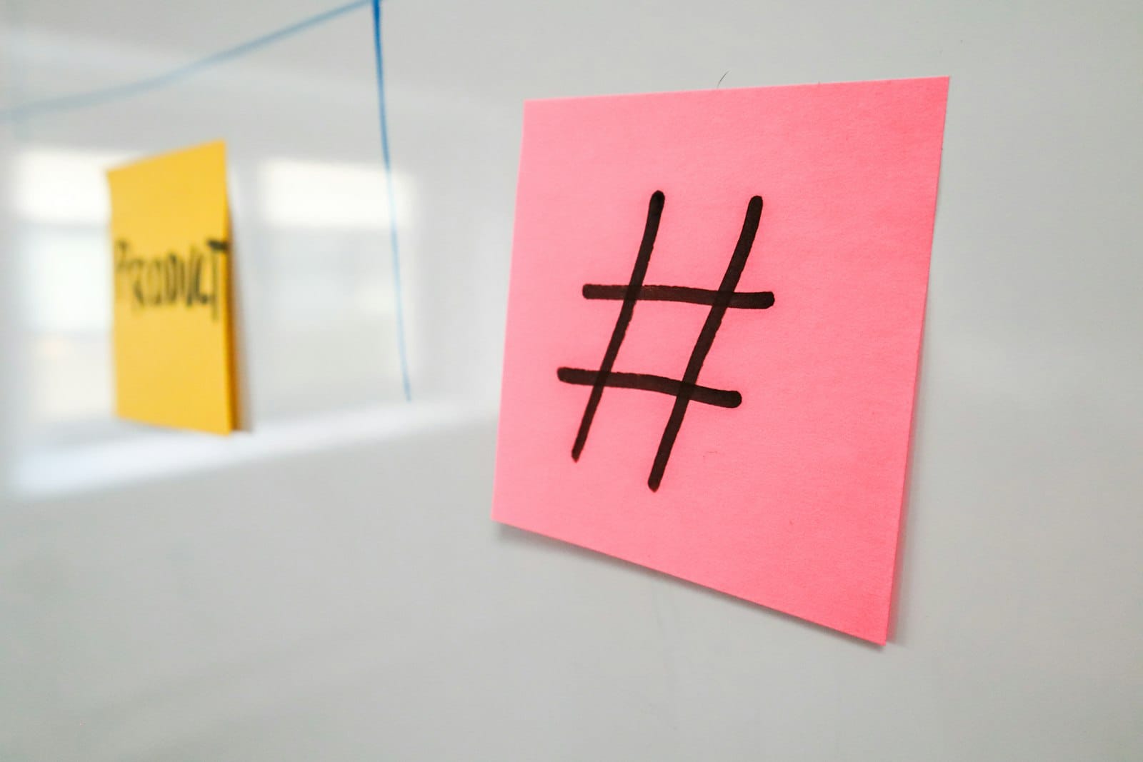 A pink sticky note marked with a hashtag next to a yellow PRODUCT category note on a whiteboard