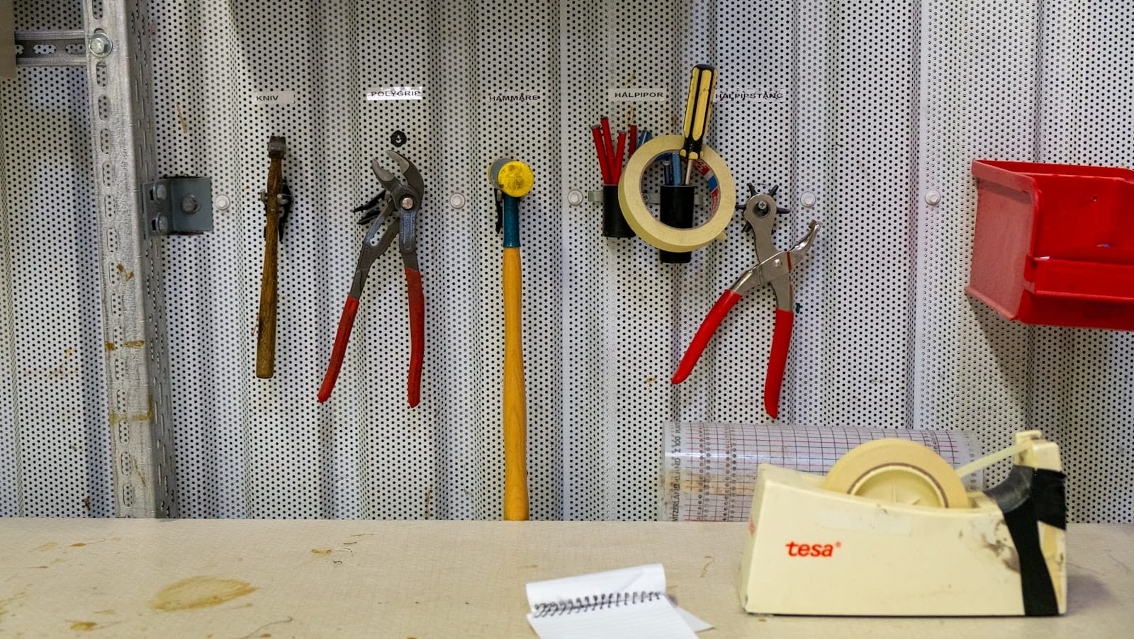 Labeled tools hanging on a workshop wall above a workbench