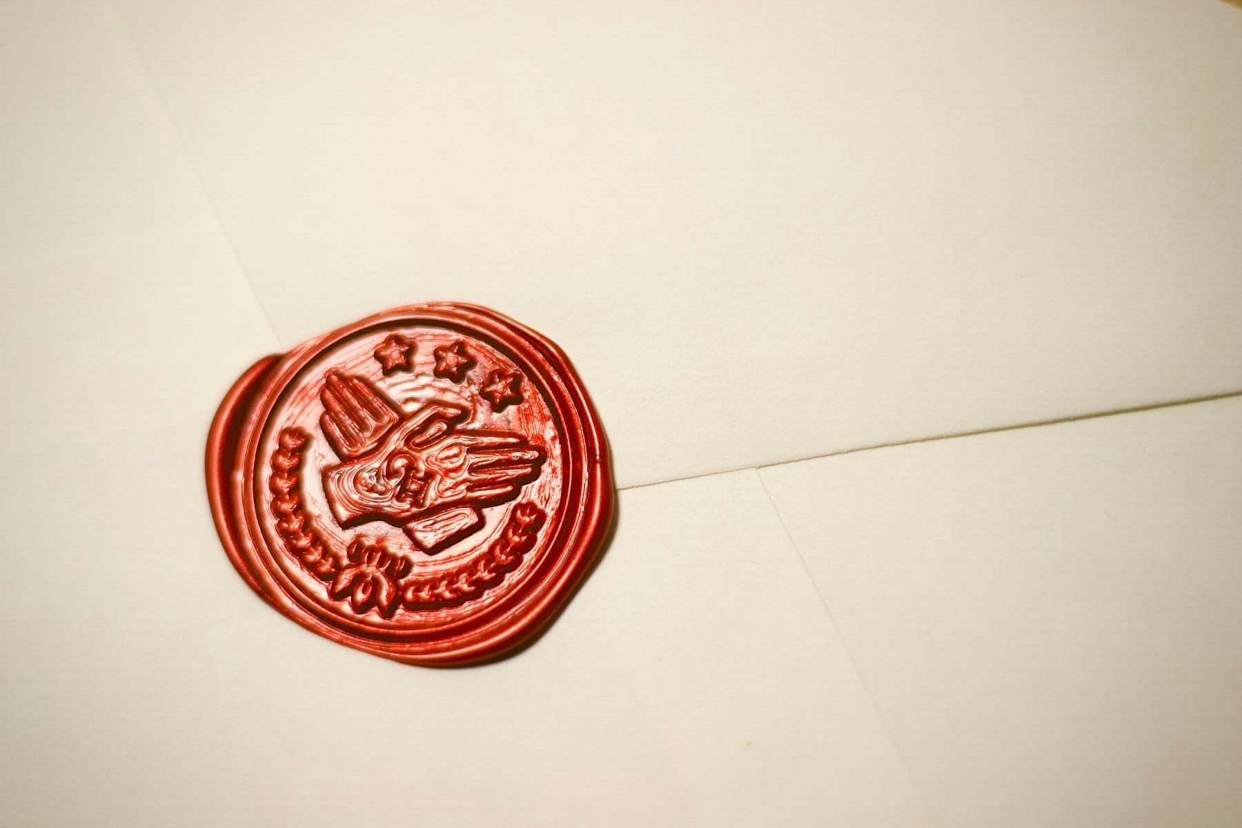 A red wax seal stamped on a cream envelope