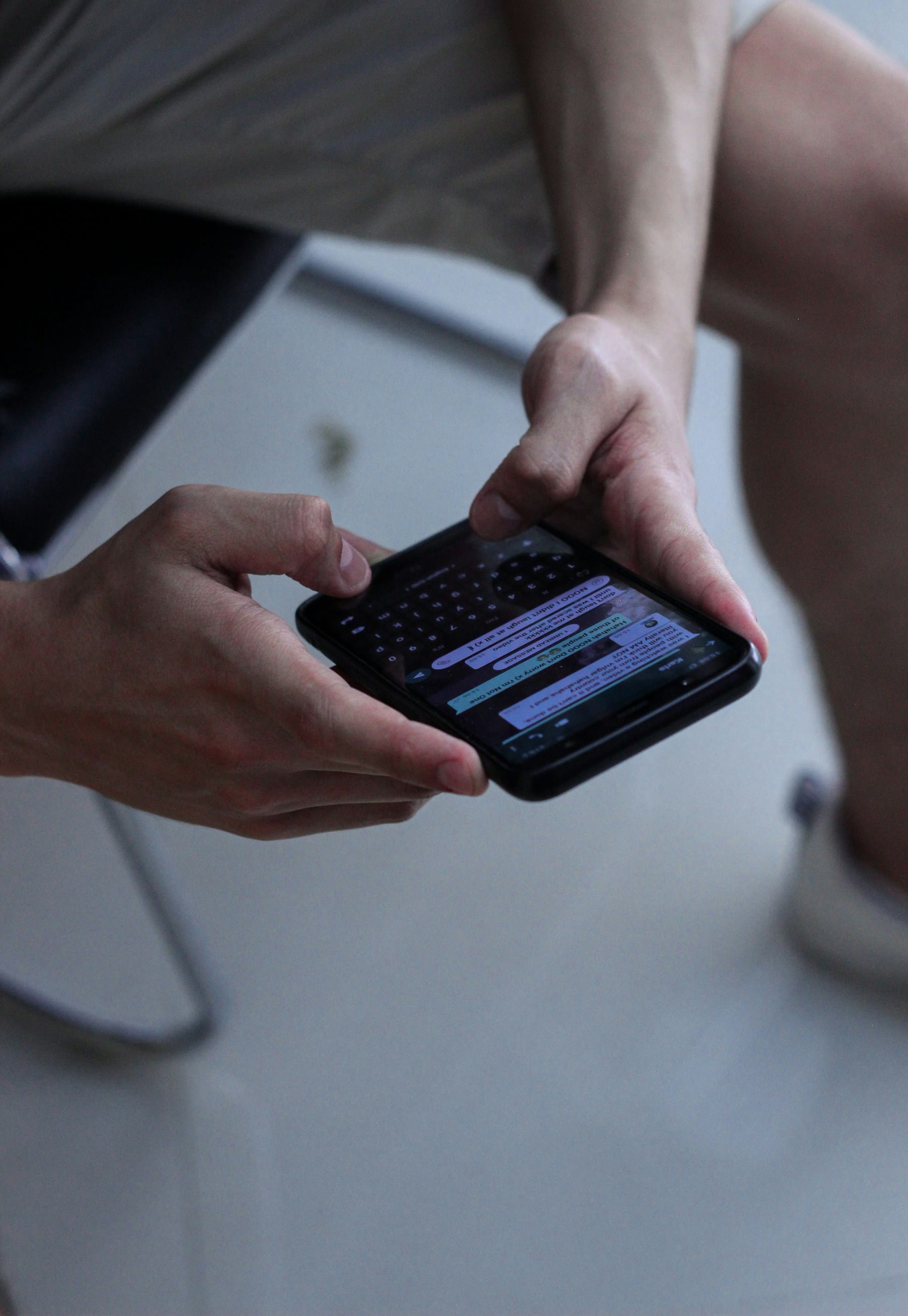 Hands typing a human chat thread on a smartphone