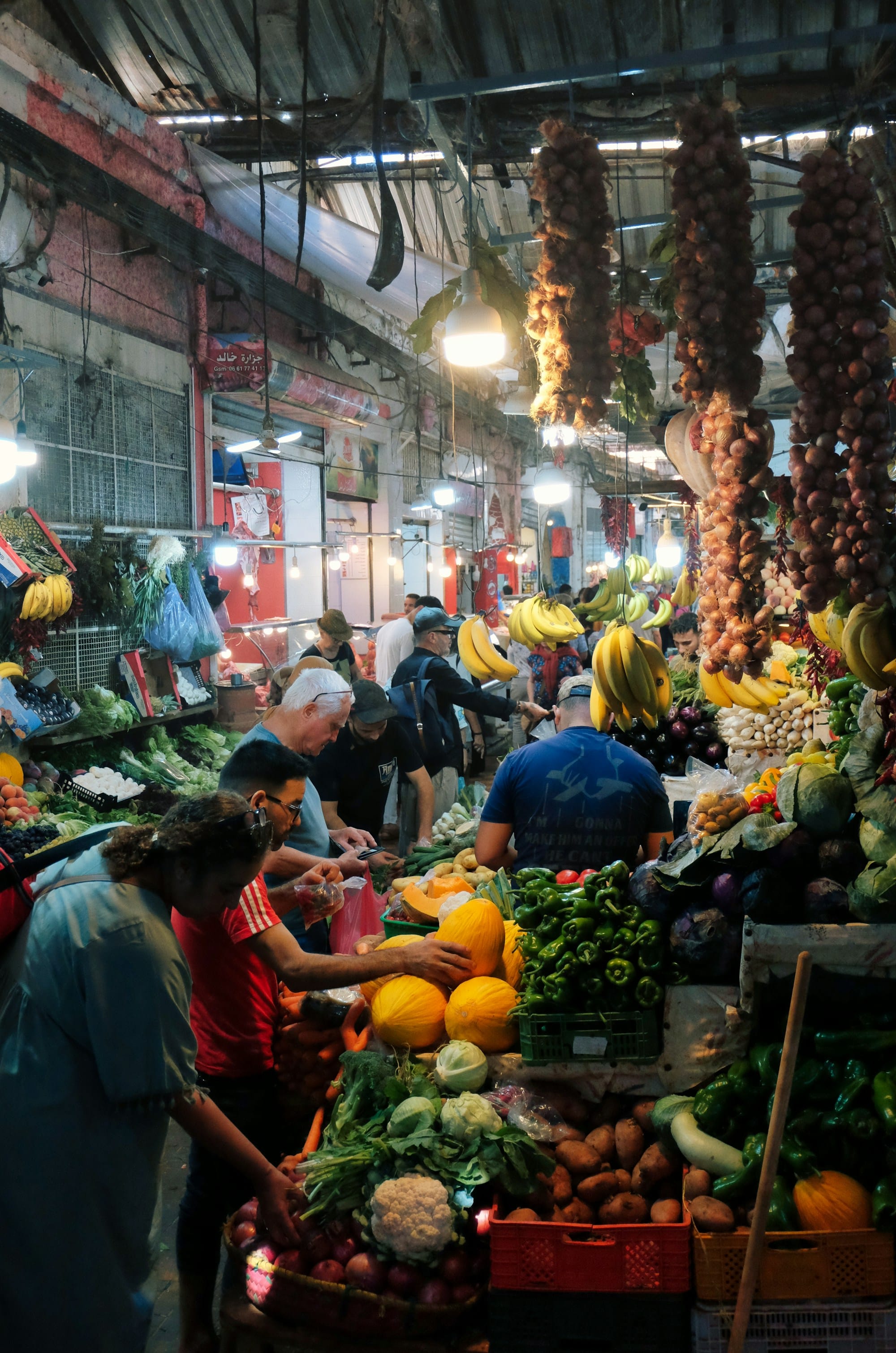 People shopping at a busy outdoor market stall with produce