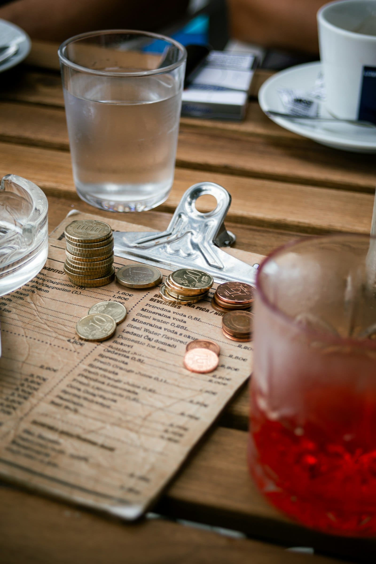 Euro coins stacked on a cafe beverage menu on a wooden table