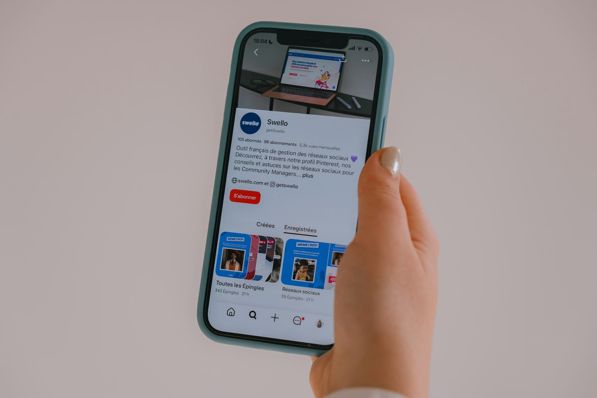 Hand holding a smartphone showing a social media profile to browse