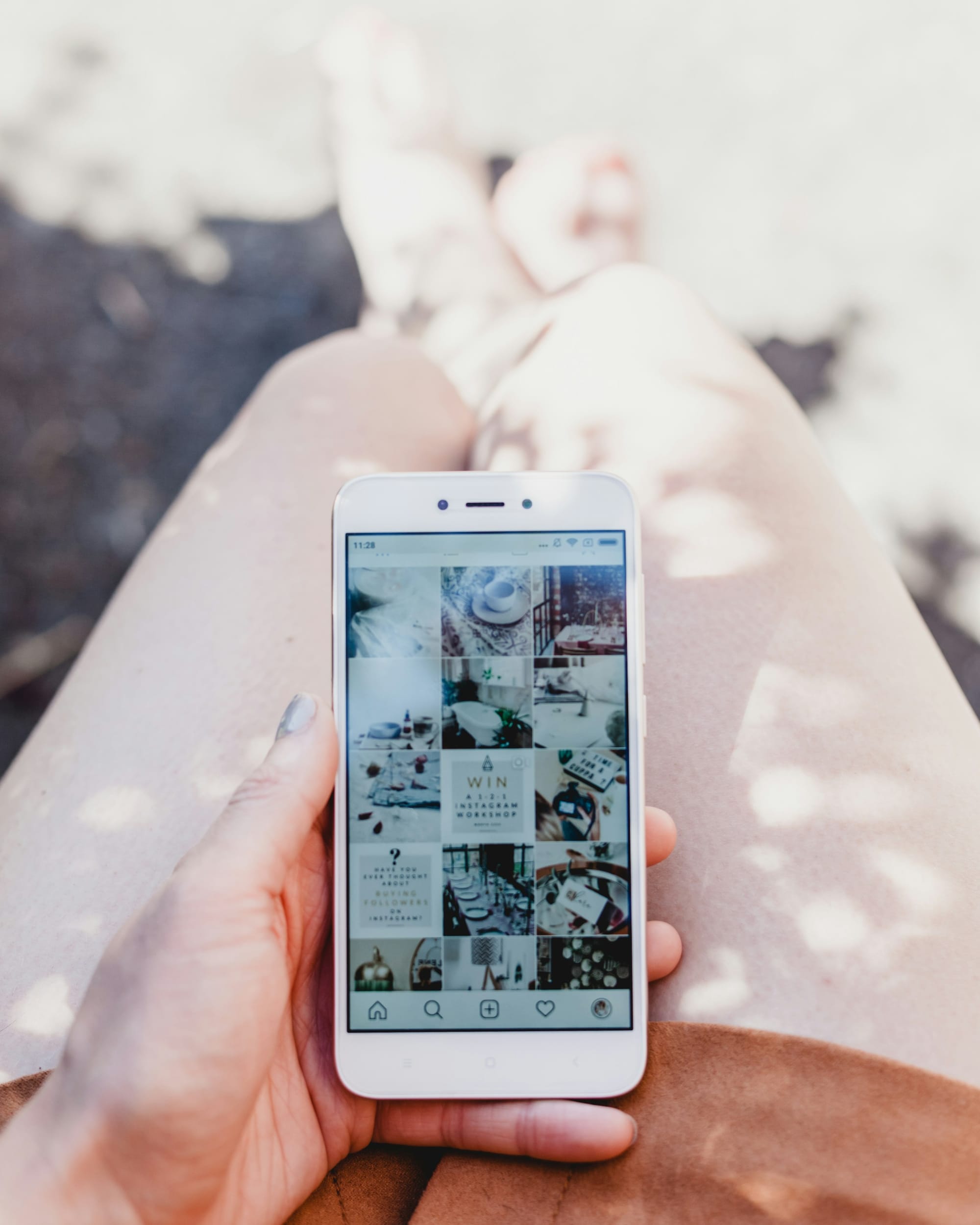 Person holding a white smartphone showing an Instagram profile grid