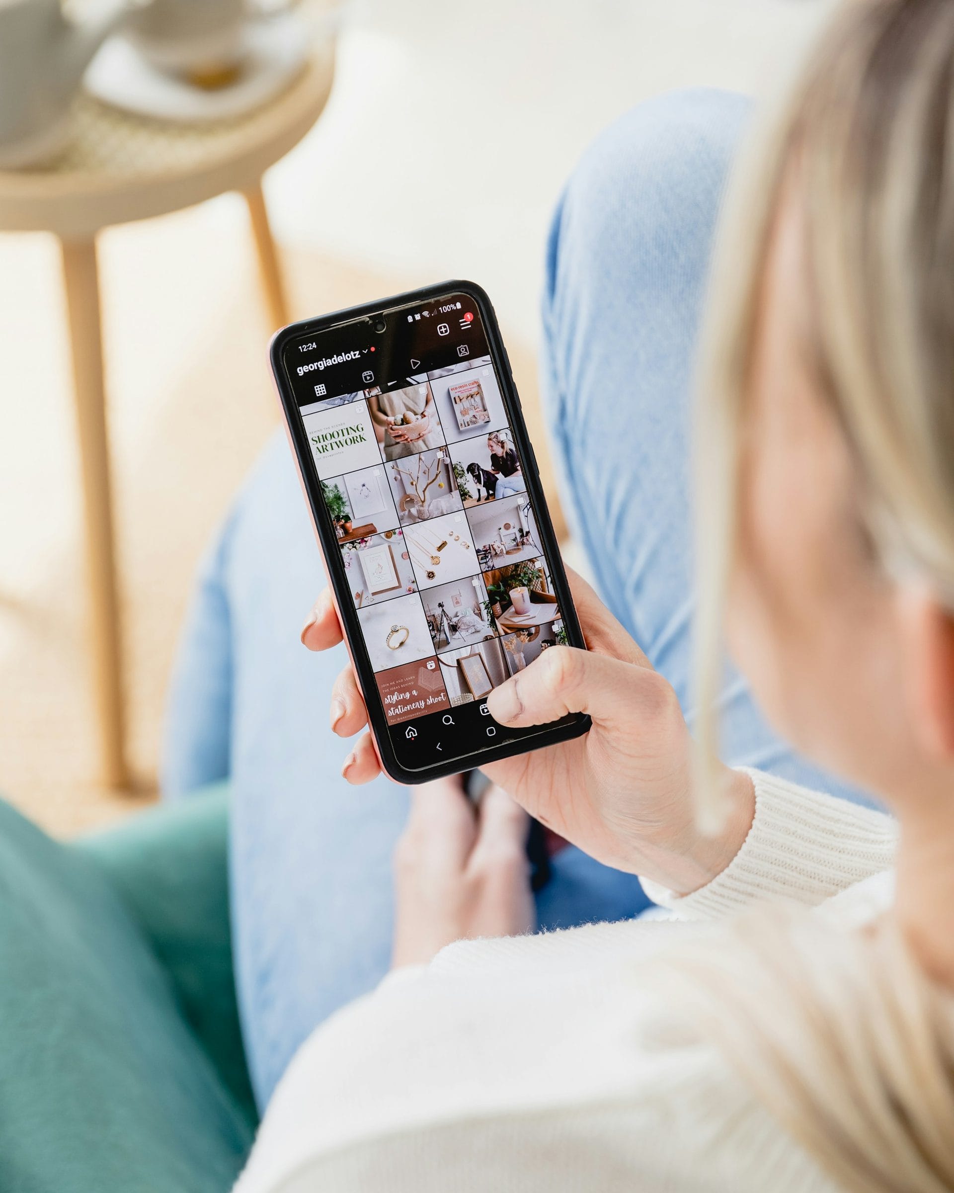 Hand holding a smartphone showing a grid of photos on a social profile