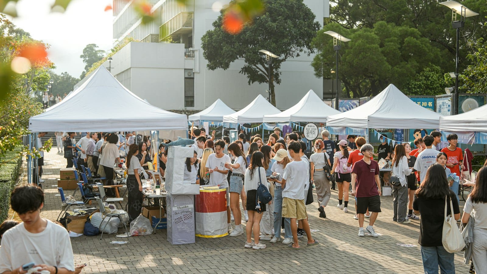People browsing stalls under white tents at an outdoor market