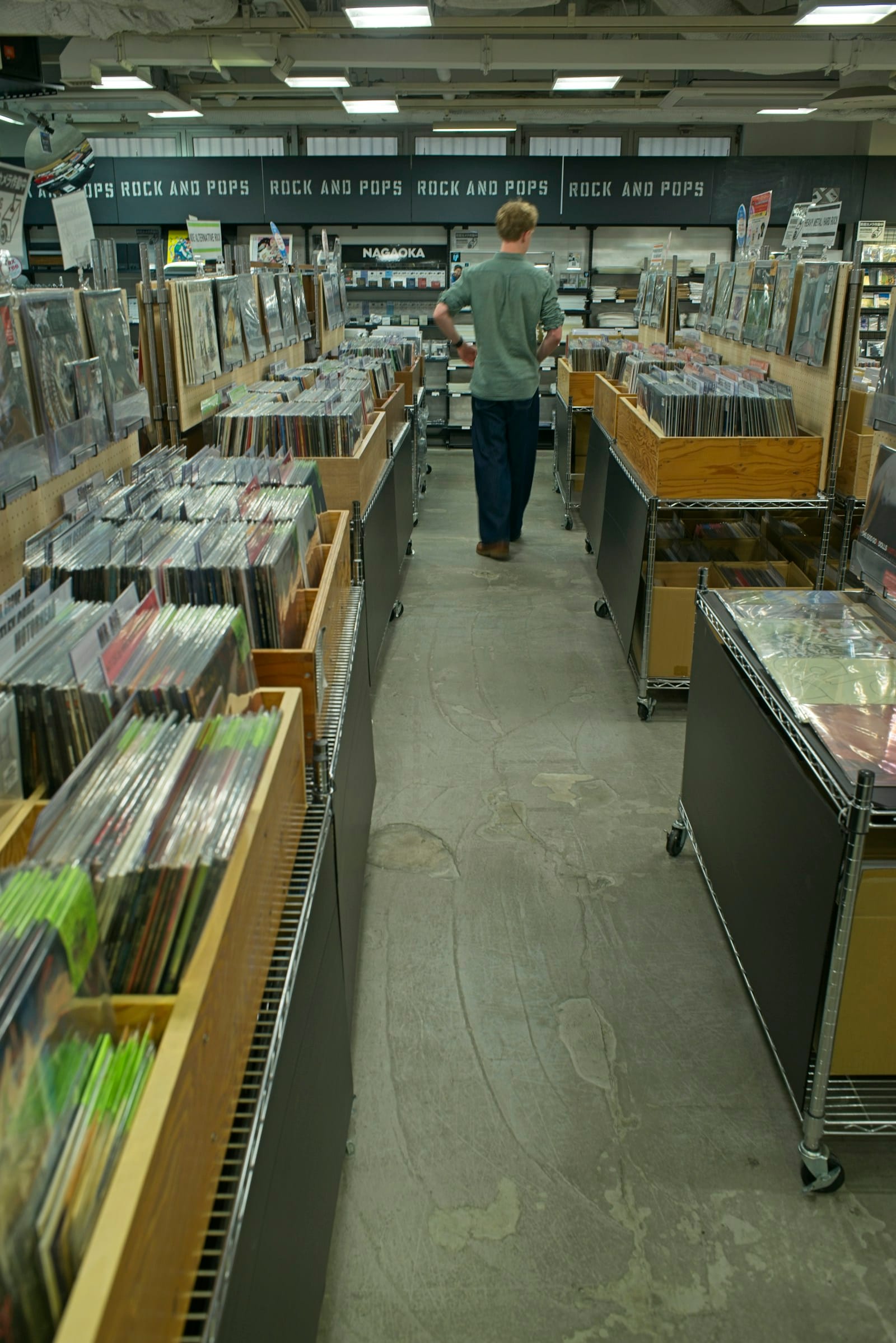 Person walking through a vinyl record store aisle