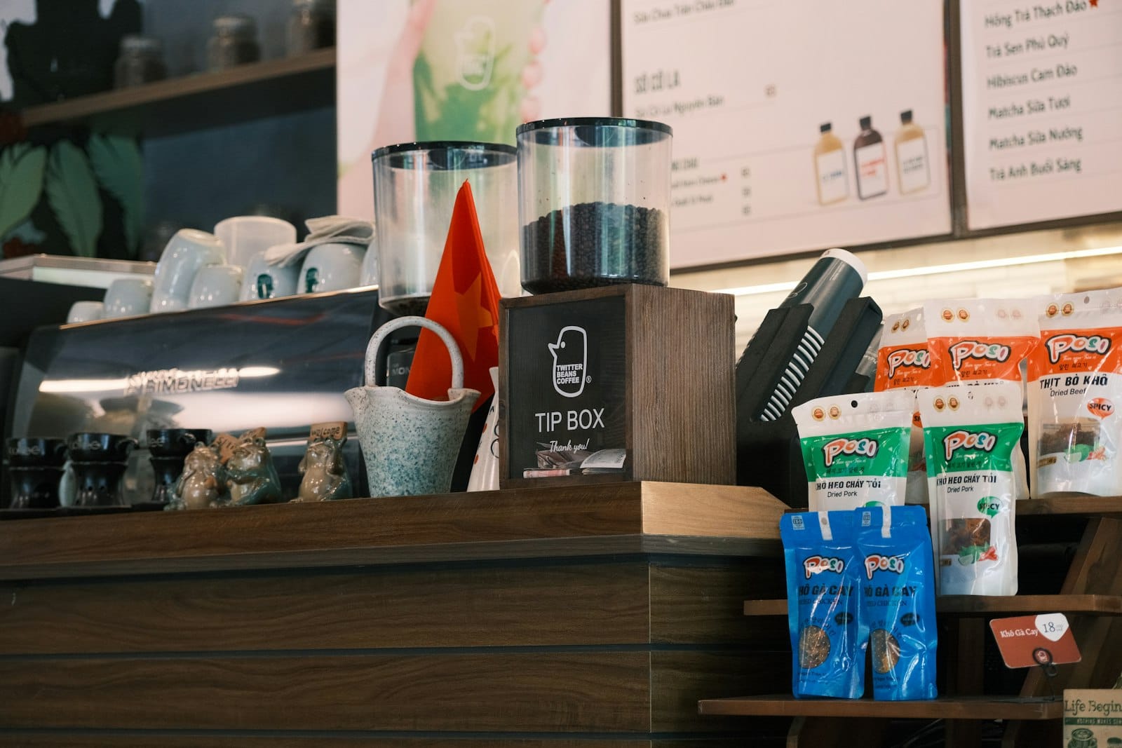 Coffee shop tip box on a counter with snacks and coffee beans