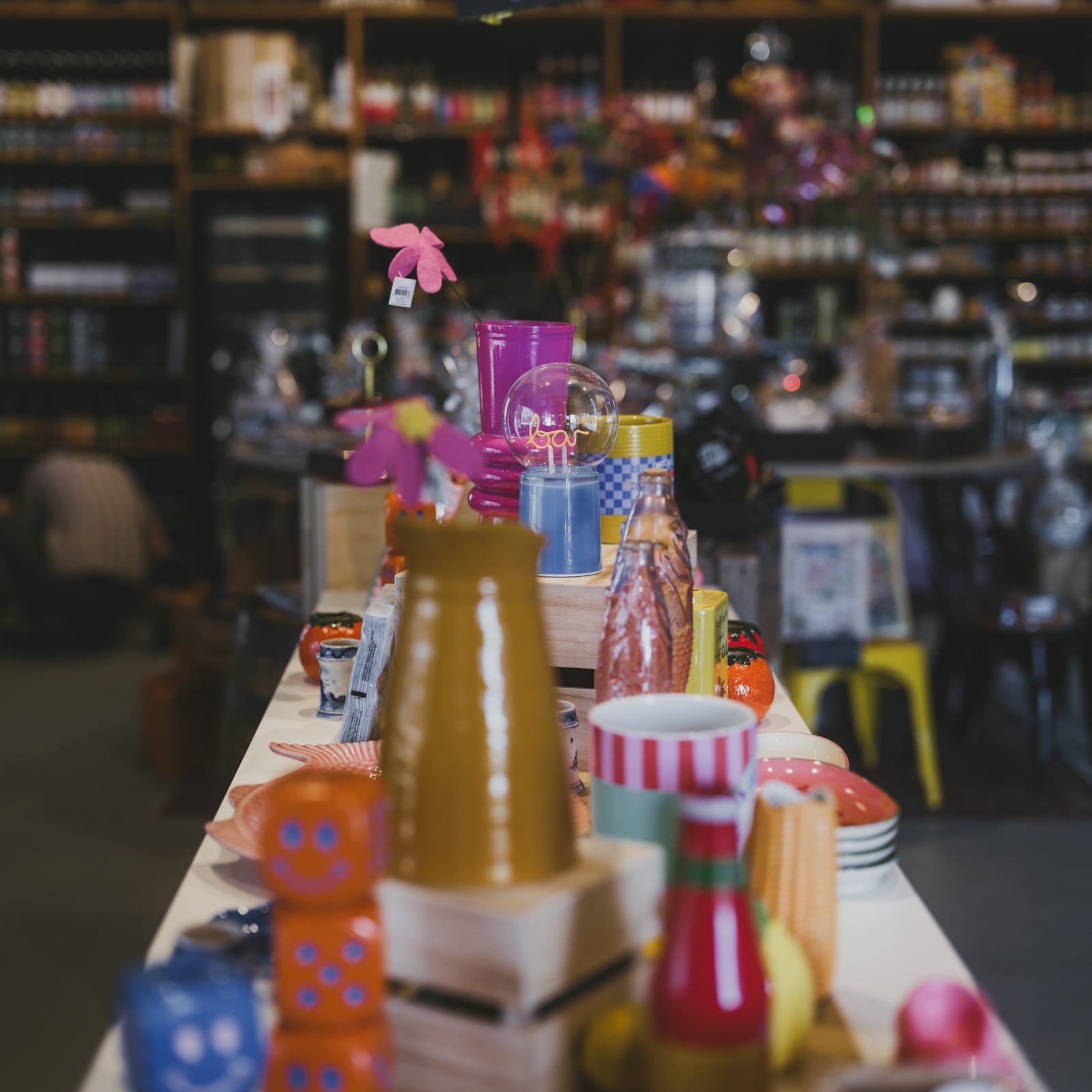 Curated gift-shop display table with colorful products on shelves behind