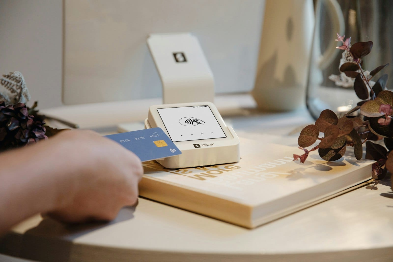 Blue bank card held near a white contactless card reader on a table