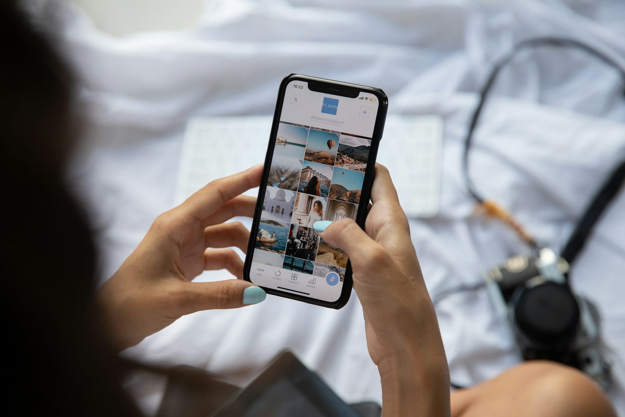 Person holding a smartphone and scrolling a three-column photo grid on a profile page