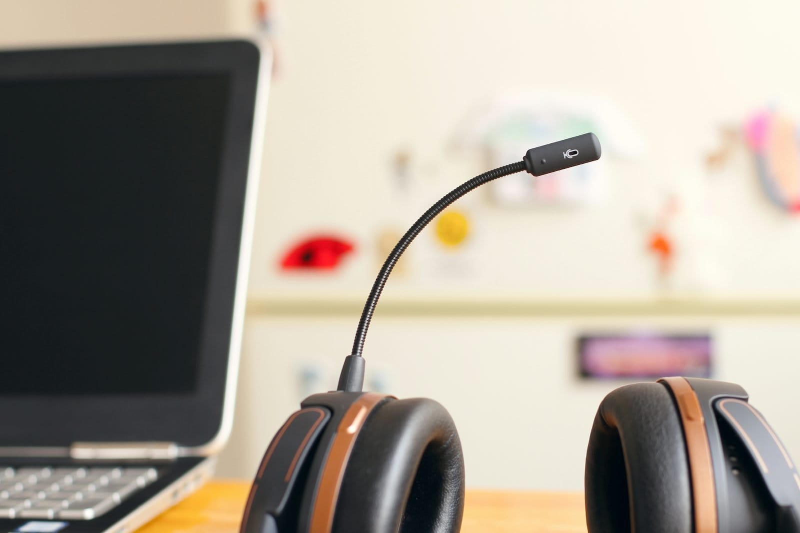 A headset with a boom microphone on a desk next to an open laptop