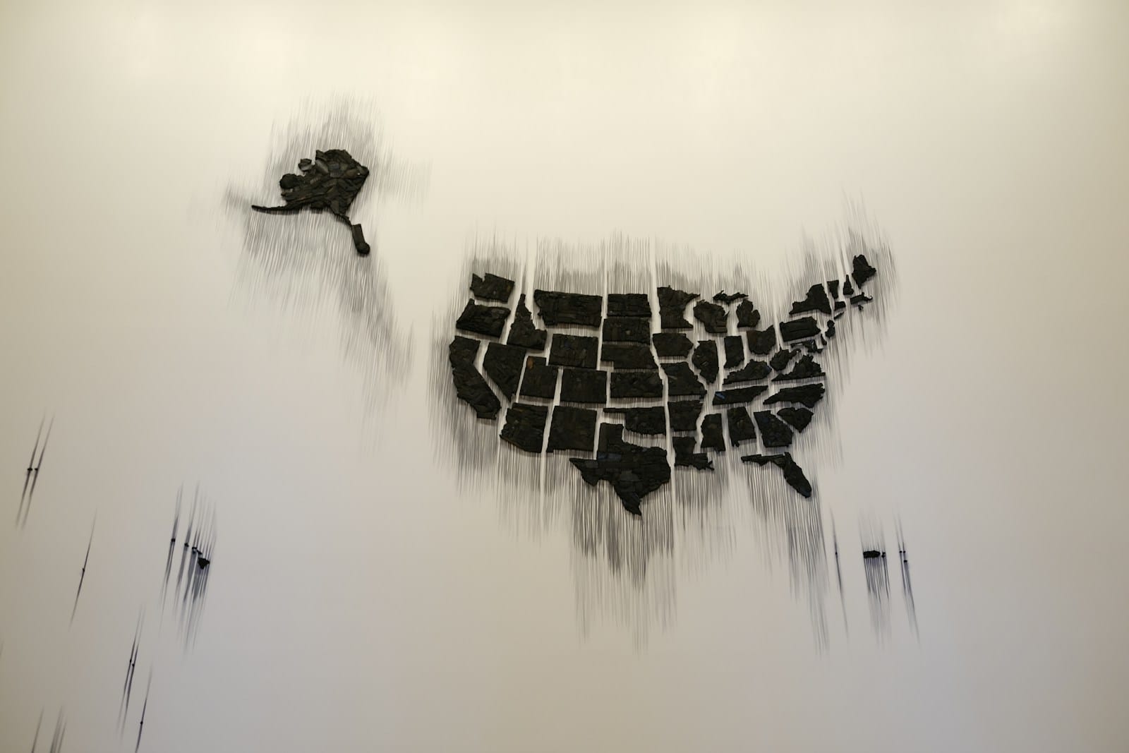 A map of the United States made of dark state-shaped pieces mounted on a pale wall