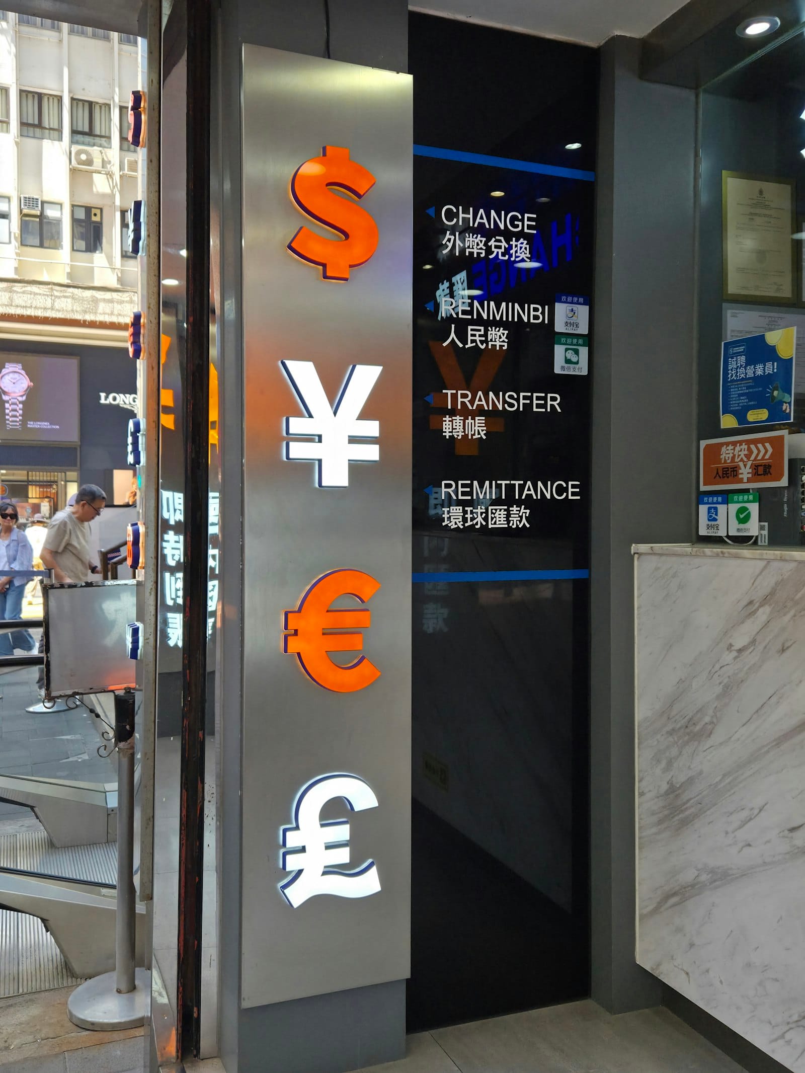Illuminated dollar, yen, euro and pound symbols on a money-exchange shop sign