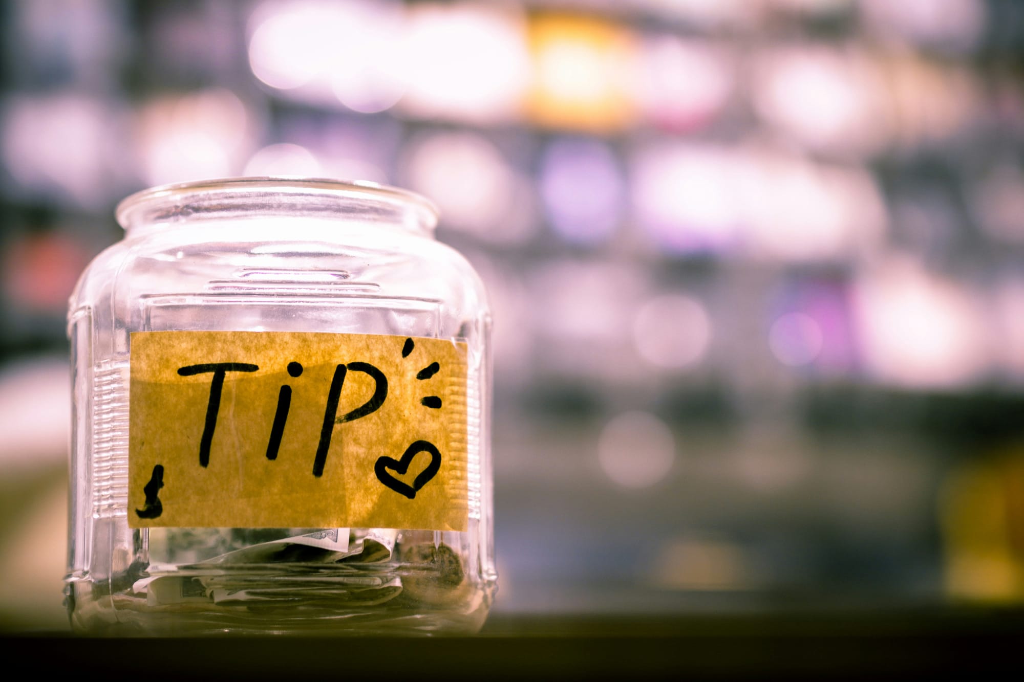 Glass tip jar with Tip label and cash inside